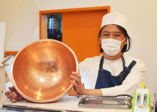 オーナー友田さんとピカピカに磨かれたクリームをたく銅の大鍋 